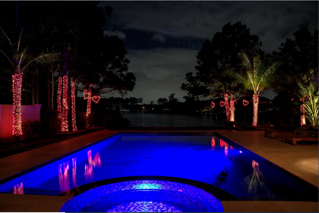 A pool surrounded by trees and red decor lights